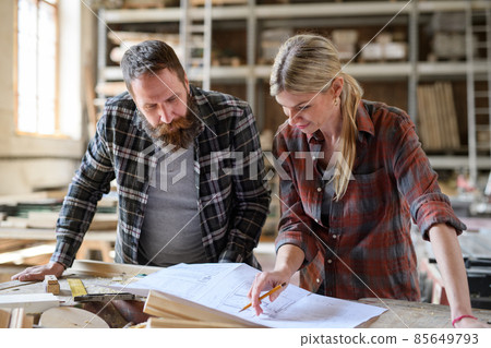 Two carpenters man and woman talking about design of products. Small business concept. Two carpenters man and woman talking about design of products. Small business concept. 85649793