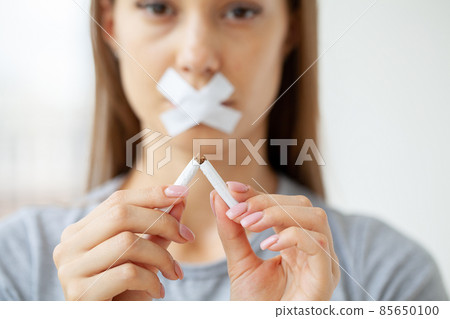 Young woman with broken cigarette, stop smoking concept. 85650100