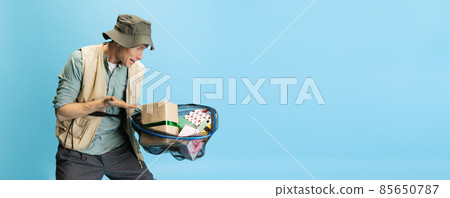 Funny young man, fisherman with fishing accessories wearing sport style clothes isolated over blue studio background 85650787