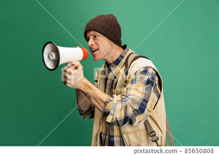 Studio shot of young man, fisherman with fishing accessories, fish rod wearing sport style clothes isolated over green background Studio shot of young man, fisherman with fishing accessories, fish rod wearing sport style clothes isolated over green background 85650808