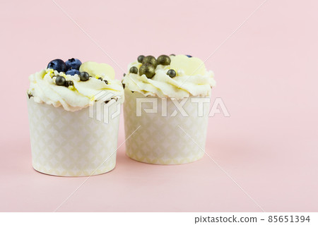 Two cupcakes on a pink background. Pair of cupcakes for lovers on a pink background Two cupcakes on a pink background. Pair of cupcakes for lovers on a pink background 85651394