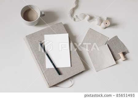 Craft still life. Beige fabric linen swatches and silk ribbon isolated on beige table background. Cup of coffee. Blank greeting card mockup, pencil on old book, diary. Mood board project flat lay, top Craft still life. Beige fabric linen swatches and silk ribbon isolated on beige table background. Cup of coffee. Blank greeting card mockup, pencil on old book, diary. Mood board project flat lay, top 85651493