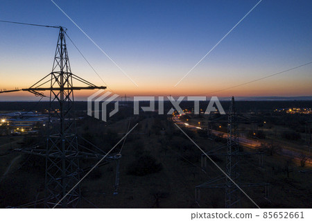 Panoramic image of power pylons against spectacular sunset red at dusk with cloudless sky Panoramic image of power pylons against spectacular sunset red at dusk with cloudless sky 85652661