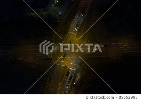 Vertical drone shot of a lighted street intersection at night with traffic Vertical drone shot of a lighted street intersection at night with traffic 85652983