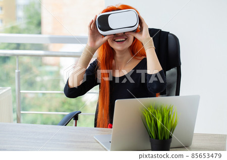 Pretty beautiful cute excited woman in VR headset trying to touch objects in virtual reality 85653479