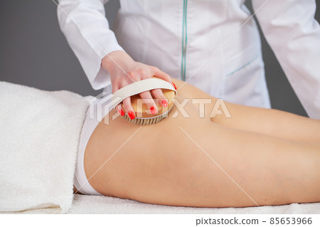 The girl is massaging the skin of the legs with a brush 85653966
