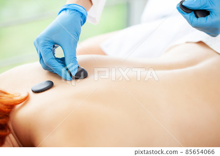 Closeup on young woman receiving hot stone massage Closeup on young woman receiving hot stone massage 85654066