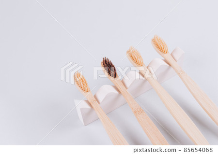 Top view on natural bamboo toothbrushes on biege plaster mold against gray background with copy space. Sustainable lifestyle, zero waste home. Selective focus. Mockup image Top view on natural bamboo toothbrushes on biege plaster mold against gray background with copy space. Sustainable lifestyle, zero waste home. Selective focus. Mockup image 85654068