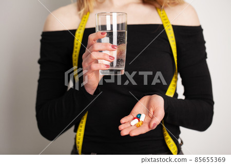 Conceptual photo of a female nutritionist holding a pill. 85655369