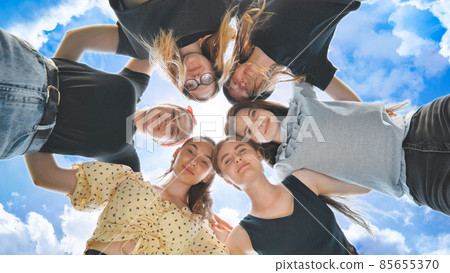 Happy girls friends hugging in a circle on the background of the fairy sky. 85655370
