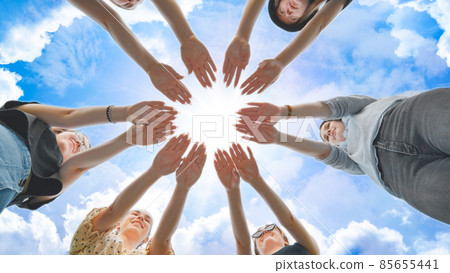 Joyful girls pull their palms to the center against the backdrop of a fabulous sky. 85655441