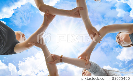Friends join their hands by the wrist and make a circle against the backdrop of a fabulous sky. Strong friendship concept. 85655460