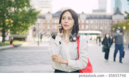 A woman talking outdoors using a smartphone A woman talking outdoors using a smartphone 85655748