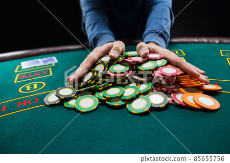 Poker player going all-in pushing his chips forward Poker player going all-in pushing his chips forward 85655756