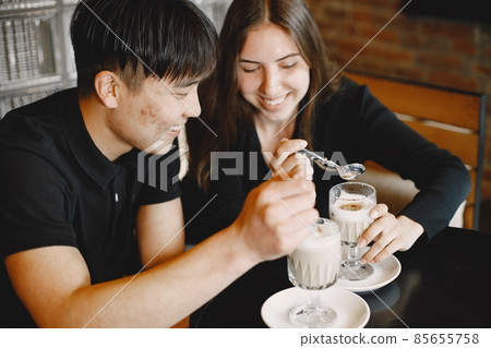 Young couple looking on a cups of cappuccino in a restaurant Young couple looking on a cups of cappuccino in a restaurant 85655758