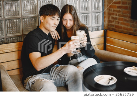 Young couple looking on a cups of cappuccino in a restaurant Young couple looking on a cups of cappuccino in a restaurant 85655759