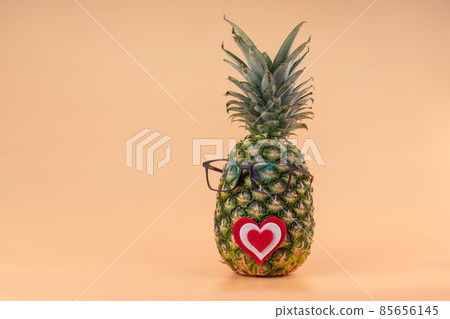 Interpretation of pineapple fruit in human image with glasses and heart concept of medicine or Valentine's day lovers. Copy space on yellow background Interpretation of pineapple fruit in human image with glasses and heart concept of medicine or Valentine's day lovers. Copy space on yellow background 85656145