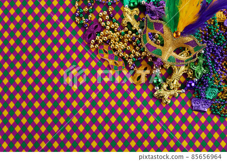 Frame of Mardi Gras Mask and colorful Mardi Gras Beads on diamond shaped background Frame of Mardi Gras Mask and colorful Mardi Gras Beads on diamond shaped background 85656964
