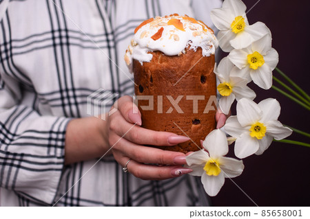 Easter cake in women's hands and flowers.  85658001