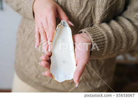 Close-up cropped shot of unrecognizable young woman holding beautifulhandmade candle in candlestick made of exotic seashell. Close-up cropped shot of unrecognizable young woman holding beautifulhandmade candle in candlestick made of exotic seashell. 85658067