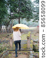 A woman walking with a yellow umbrella in the snow 85658099