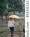 A woman walking with a yellow umbrella in the snow 85658102