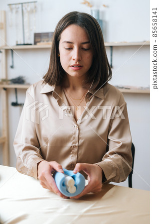 Vertical portrait of attractive young woman artisan taking out beautiful white piece of author candle of silicone mold. Vertical portrait of attractive young woman artisan taking out beautiful white piece of author candle of silicone mold. 85658141