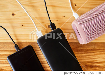 Powerbank charges smartphone and portable speaker using usb. Close-up, selective focus 85660106