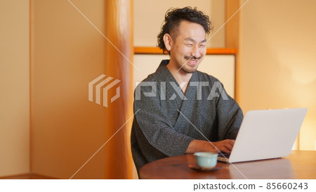 A man with a beard who uses a laptop in a Japanese-style room 85660243