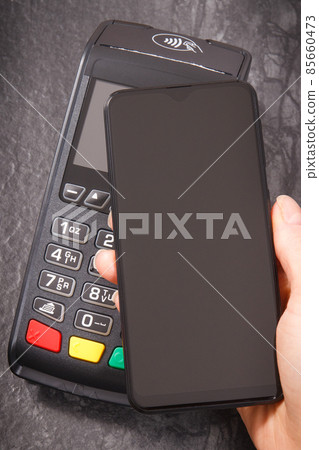 Hand of woman using payment terminal and smartphone to cashless paying. Finance concept Hand of woman using payment terminal and smartphone to cashless paying. Finance concept 85660473
