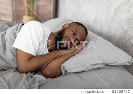 Black man lying in bed and thinking Black man lying in bed and thinking 85660737
