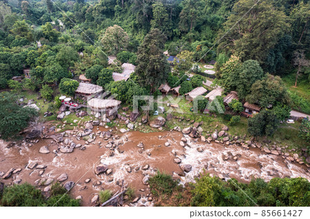 Aerial view of wooden bungalow in tropical rainforest with natural rapids in the valley 85661427