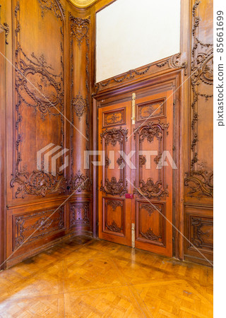 Closed elegant lumber door with engraved decorations, installed in wooden ornamental archway Closed elegant lumber door with engraved decorations, installed in wooden ornamental archway 85661699