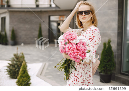 Young blonde woman standing near cafe and holding a bouquet of f Young blonde woman standing near cafe and holding a bouquet of f 85661899