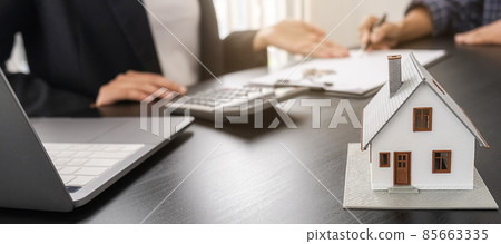 House model with agent and customer discussing for contract to buy, get insurance or loan real estate or property. House model with agent and customer discussing for contract to buy, get insurance or loan real estate or property. 85663335