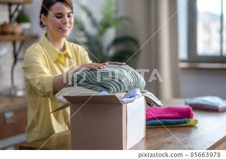 Happy lady placing sweaters in the carton Happy lady placing sweaters in the carton 85663978