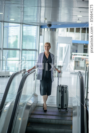 Airport passenger posing for the camera on the moving staircase 85664175