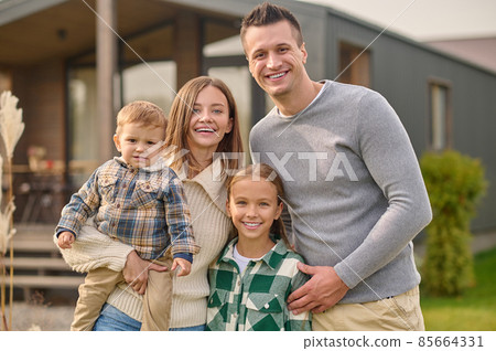 Young parents and children embracing standing looking at camera 85664331