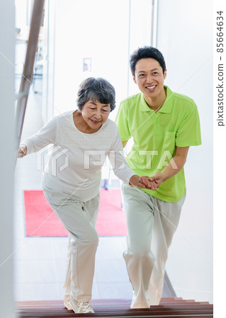 Senior female climbing stairs and long-term care staff Photographing cooperation: Japanese language school attached to Chuo Institute of Technology 85664634