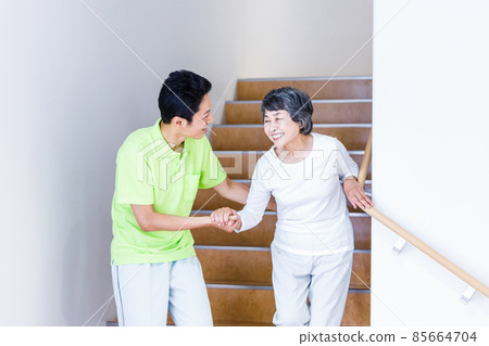 Senior female going down the stairs and long-term care staff Photographing cooperation: Japanese language school attached to Chuo Institute of Technology 85664704