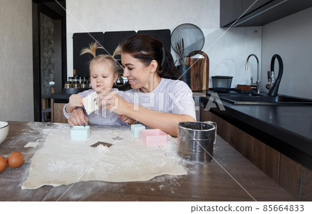 Happy loving family cooking bakery together. Mother and daughter-girl cook cookies and have fun in the kitchen. Homemade food and a little helper. 85664833