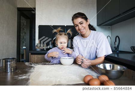 Happy loving family cooking bakery together. Mother and daughter-girl cook cookies and have fun in the kitchen. Homemade food and a little helper. 85664884