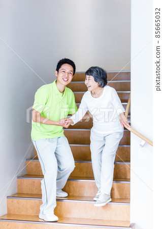 Senior female going down the stairs and long-term care staff Photographing cooperation: Japanese language school attached to Chuo Institute of Technology Senior female going down the stairs and long-term care staff Photographing cooperation: Japanese language school attached to Chuo Institute of Technology 85665032