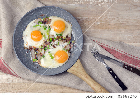 fried eggs with bacon and green onions in a frying pan fried eggs with bacon and green onions in a frying pan 85665270