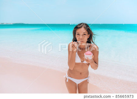 Ice cream dessert on beach. Happy Asian woman eating delicious frozen fruit yogurt or Acai smoothie bowl healthy food on Caribbean beach vacation travel Ice cream dessert on beach. Happy Asian woman eating delicious frozen fruit yogurt or Acai smoothie bowl healthy food on Caribbean beach vacation travel 85665973