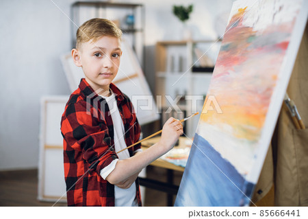Talented boy drawing with brush and paints on easel 85666441