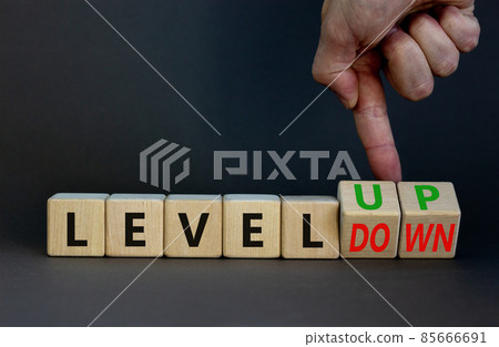 Level up or down symbol. Businessman turns cubes and changes concept words level down to level up. Beautiful grey table, grey background. Business and level up or down concept. Copy space. 85666691