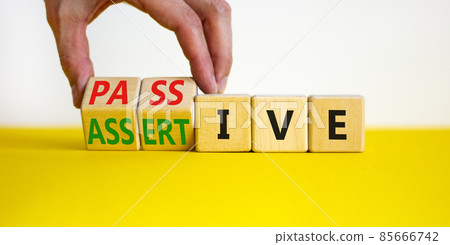 Passive or assertive symbol. Businessman turns wooden cubes and changes the word passive to assertive. Beautiful white background, copy space. Business, psychological passive assertive concept. Passive or assertive symbol. Businessman turns wooden cubes and changes the word passive to assertive. Beautiful white background, copy space. Business, psychological passive assertive concept. 85666742
