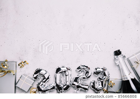 New Year 2023 gray background flat lay. Top view on 2023 balloon silver metallic numbers with grey gift boxes, golden ribbon. Invitation or greeting card. Festive mood. Opened champagne wine bottle 85666808