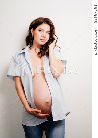 attractive pregnant woman in jeans and a shirt on a naked body. women's health 85667262